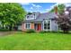 Charming front exterior featuring a brick facade and inviting red door, with mature trees and a lush lawn at 7430 Railway Ct, Indianapolis, IN 46256