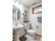 Bathroom featuring a pedestal sink, toilet, round mirror, and a window at 7850 S Mooresville Rd, Indianapolis, IN 46113