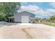 Spacious building featuring a garage door, side door, and carport, with ample gravel parking at 7850 S Mooresville Rd, Indianapolis, IN 46113