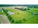 Expansive aerial view of a brick home, a pond, and a large grassy yard with a white fence at 8371 N 400 W, Fairland, IN 46126