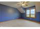 Bright bedroom featuring blue walls, a ceiling fan, carpet, and a large window allowing ample natural light at 8371 N 400 W, Fairland, IN 46126