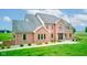 Elegant brick home showcasing a manicured front lawn with green shrubbery, mature trees, and a paved walkway at 8371 N 400 W, Fairland, IN 46126