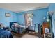 Bright blue bedroom featuring hardwood floors, two beds, and a sunny window at 9125 Timpani Way, Indianapolis, IN 46231