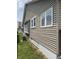 Side view of house shows vinyl siding, basement foundation, and landscaped yard at 1033 Cottage Ave, Columbus, IN 47201