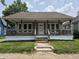 Charming single-story home featuring a cozy front porch with wood railings and a well-maintained lawn at 1033 Cottage Ave, Columbus, IN 47201