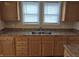 Kitchen features a double stainless steel sink with oak cabinets and granite countertops under two windows at 1033 Cottage Ave, Columbus, IN 47201