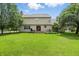 Large backyard with a well-maintained lawn, mature trees, and a wooden deck with seating at 10410 Trillium Ct, Noblesville, IN 46060