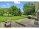 Backyard view of a wooden deck with furniture and a grill, surrounded by a well-manicured lawn and mature trees at 10410 Trillium Ct, Noblesville, IN 46060