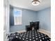 A bedroom with blue walls and neutral carpet featuring a black desk and a window with blinds at 10410 Trillium Ct, Noblesville, IN 46060
