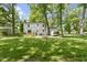 Landscaped backyard featuring a lush lawn, mature trees, wooden sauna, and well-maintained home at 11461 N College Ave, Carmel, IN 46032