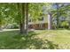A well-kept two-story home with brick and vinyl siding, a brick chimney, and a green lawn surrounded by mature trees at 11461 N College Ave, Carmel, IN 46032