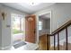 Bright foyer with tile flooring, coat rack, stairs with wood railing and view of the hardwood flooring in next room at 11461 N College Ave, Carmel, IN 46032
