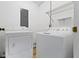 Bright laundry room features a white washer and dryer with shelving and an electrical panel at 11461 N College Ave, Carmel, IN 46032