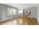 Bright living room featuring hardwood floors, large windows, and neutral paint; open layout and staircase access at 11461 N College Ave, Carmel, IN 46032