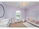 Bright bedroom showcases purple walls, a crib and modern decor, creating a comfortable and inviting atmosphere at 11521 Short Iron Ln, Indianapolis, IN 46235