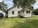 Quaint home featuring light yellow siding, a simple front yard, and mature trees at 1201 N Canal St, Alexandria, IN 46001