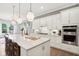 Bright kitchen features white cabinets, stainless steel appliances, a large island, and hardwood floors at 12594 Pasco St, Fishers, IN 46038