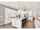Bright kitchen features white cabinetry, stainless appliances, large island with seating, and pendant lighting at 12594 Pasco St, Fishers, IN 46038