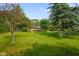Expansive green backyard featuring mature trees and a charming brick home with an American flag waving proudly at 1506 Bowman Dr, Greenfield, IN 46140