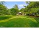 Lush green backyard featuring mature trees and a brick home with a spacious deck, perfect for outdoor entertaining at 1506 Bowman Dr, Greenfield, IN 46140