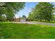 Brick ranch-style house on a large lawn, featuring an attached garage and mature trees at 1506 Bowman Dr, Greenfield, IN 46140