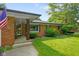 Charming brick home entrance with covered porch, decorative columns, and landscaped garden at 1506 Bowman Dr, Greenfield, IN 46140