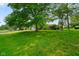 Manicured front lawn with mature trees and a view of the brick ranch house with an attached garage at 1506 Bowman Dr, Greenfield, IN 46140