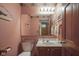 Powder room with pink walls, wood trim, and a decorative mirror at 17916 Racebrook Ct, Noblesville, IN 46062