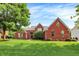 Beautiful red brick home with a well-manicured lawn and mature trees under a blue sky at 2614 Daylily Ct, Westfield, IN 46074