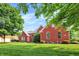 Charming red brick home with a lush green lawn, mature trees, and a well-kept garden at 2614 Daylily Ct, Westfield, IN 46074