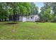 View of the backyard with a trampoline, deck, and yard with mature trees at 2640 S Silcox Rd, Paragon, IN 46166