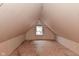 Unfinished attic space with plywood floors, drywall, and a small window view at 305 N Warman Ave, Indianapolis, IN 46222