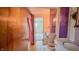 Bathroom with a tub/shower combo featuring a pink curtain and adjacent toilet and sinks with purple accents and vintage wallpaper at 3215 E 10Th St, Anderson, IN 46012