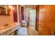 Bathroom with a tub/shower combo featuring a pink curtain and adjacent toilet and sinks with purple accents and vintage wallpaper at 3215 E 10Th St, Anderson, IN 46012