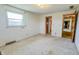 A bedroom featuring a window, tan painted walls, a door, and carpeted floor at 3215 E 10Th St, Anderson, IN 46012