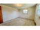 A bedroom featuring a window, tan painted walls, a door, and carpeted floor at 3215 E 10Th St, Anderson, IN 46012