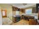 Outdated kitchen featuring wood cabinets, tile countertops, and older appliances at 3215 E 10Th St, Anderson, IN 46012
