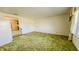 Living room with textured green carpet, window with coverings, and view into dining area at 3215 E 10Th St, Anderson, IN 46012