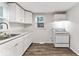 White kitchen with new wood-look flooring, cabinets, countertops, white appliances, and natural light at 3453 W 12Th St, Indianapolis, IN 46222