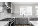 Kitchen close-up featuring grey cabinets, stainless steel appliances, and unique tile backsplash at 449 Shade St, Carmel, IN 46290
