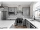 Well-lit kitchen featuring grey cabinetry, stainless appliances, patterned backsplash, and hardwood floors at 449 Shade St, Carmel, IN 46290