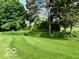 Landscaped backyard featuring plush green lawn and mature trees with views of the home at 458 Burlington Ln, Carmel, IN 46032