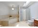 Bathroom featuring a soaking tub, glass block shower, and neutral tile for a spa-like experience at 5108 Riverview Dr, Indianapolis, IN 46208