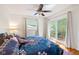 Bright bedroom featuring a ceiling fan, floral bedding, and sliding glass door to a private balcony with outdoor seating at 5108 Riverview Dr, Indianapolis, IN 46208