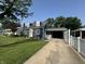 A cozy blue house with dormers, carport, white fence and well-manicured lawn at 537 N 17Th St, Noblesville, IN 46060