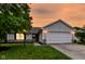 Charming single-story home with a well-maintained lawn and inviting two-car garage at sunset at 5651 Pine Knoll Blvd, Noblesville, IN 46062