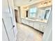 Bright bathroom featuring double sinks, tile flooring, framed mirrors, and open access to the walk-in closet at 581 Roosevelt St, Fortville, IN 46040