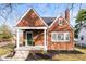Charming brick home featuring a cozy front porch, green door, and manicured landscaping at 6640 E Washington St, Indianapolis, IN 46219