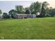 Large backyard with a lawn, brick house, patio furniture, and mature trees at 7870 E County Road 150 S, Avon, IN 46123