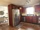 Traditional kitchen features stainless steel refrigerator, dark wood cabinetry, and a window over the sink at 7870 E County Road 150 S, Avon, IN 46123
